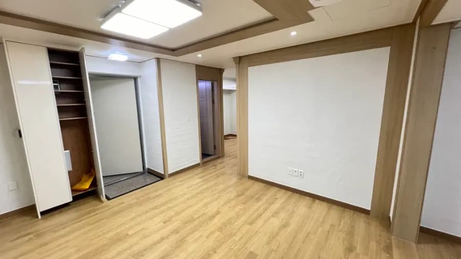 흰 벽지로 도배를 마친 거실 벽과 현관